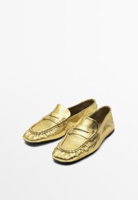 Goldene Lederloafers mit strukturiertem Finish, einem niedrigeren Profil, gesteppten Details und einem abgerundeten Zehenbereich.