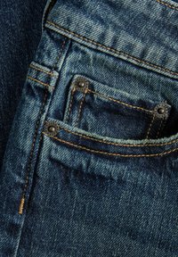 Podrobni posnetek jeans tkanine v temno modri barvi z izgorevanjem. Majhna sprednja žepa z ojačenimi koti in natančnimi bronastimi nitkami. Oranžno prešito.