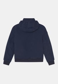 Granatowa kurtka z kapturem wykonana z gładkiej tkaniny, z prążkowanymi mankietami i obszyciem, o prostym, minimalistycznym wzornictwie bez widocznych logo czy wzorów.