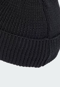 Zwarte gebreide beanie met een gestructureerd ribbenontwerp. De stof lijkt zacht, met een aansluitende pasvorm en een omgeslagen rand aan de onderkant.
