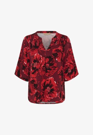 Röd blus med stora mörkröda och svarta blommönster, halvärmar och V-ringning med smockdetaljer på axlarna.