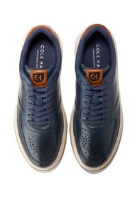 Marina lädersneakers med perforerade detaljer, rund tå och bruna accenter på tungan och hälen, samt en vit gummisula.