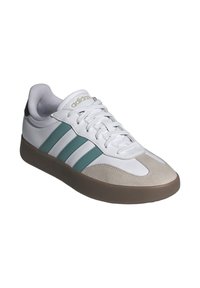 Zapatillas deportivas blancas con rayas en color teal y una punta de gamuza, con una suela de goma texturizada y un cuello acolchado para mayor comodidad.