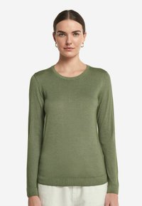 Grön långärmad tröja med rund halsringning, tillverkad av mjukt material. Har ribbade ärmslut och nederkant, åtsittande silhuett och slät yta.