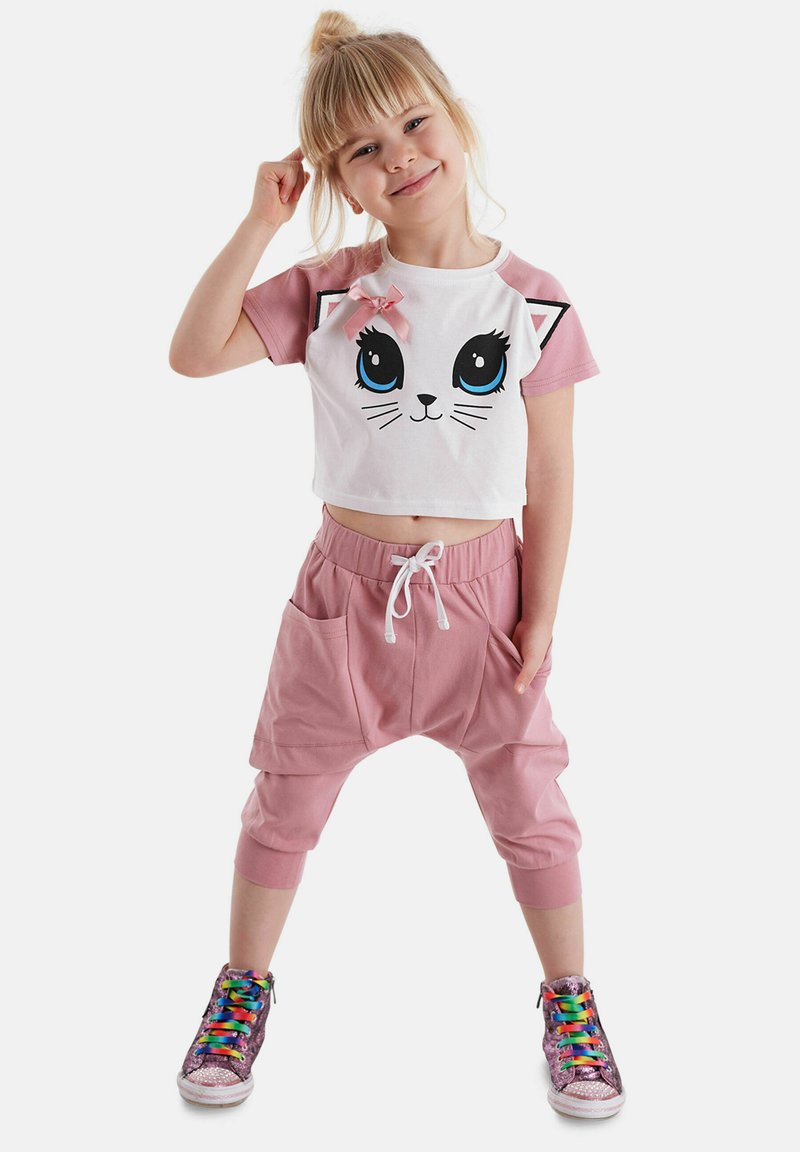 Conjunto infantil en rosa y blanco con un gráfico de cara de gato. Top corto de manga corta y pantalones jogger rosa de corte holgado con bolsillos y cintura ajustable con cordón.