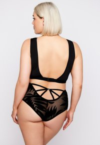 Schwarzes Bikiniset mit einem tief ausgeschnittenen Oberteil und hochgeschnittenem Unterteil aus transparenter schwarzer Stoff mit Blattmuster, akzentuiert durch Riemchendetails.