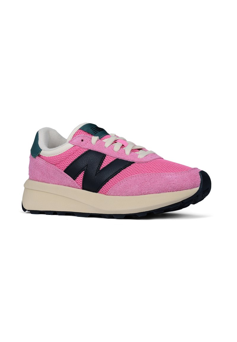 Rosa und beige New Balance Sneakers mit schwarzem "N"-Logo, weißen Schnürsenkeln, grünem Fersenbereich und schwarzer Gummisohle, seitliche Ansicht auf weißem Hintergrund.