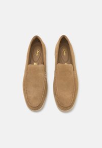 Suedeslippers i beige med en smooth finish, rund tå og stikking detaljering. Lett polstring og en fleksibel såle synlig.