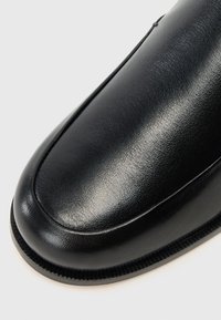 Čierna kožená topánka s okrúhlym prstom, hladkým povrchom a jemným šitím. Má štruktúrovanú podrážku pre lepšiu priľnavosť a trvanlivosť.