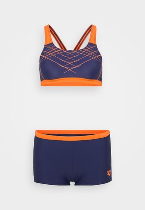 Mørkeblå badedragtssæt med sports-BH med orange accenter og geometrisk mønster, suppleret med matchende shorts med orange taljebånd.