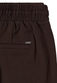 Hnědý elastický pás s nařasenou strukturou, výbava s malou kovovou značkou. Hladká tkanina se jemným leskem, zahrnuje detail kapsy.