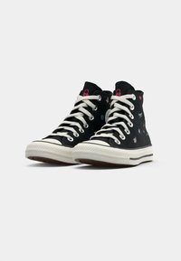Mustad mustad sneakers valge lace ja kummitald, mille külgedel on värvilised tikandid lillede ja liblikate motiividega.