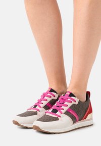 Sneaker sportive con upper in tela marrone cioccolato, lacci rosa, dettagli in suede bianco e tacco rosso. Suola in gomma per una buona aderenza.