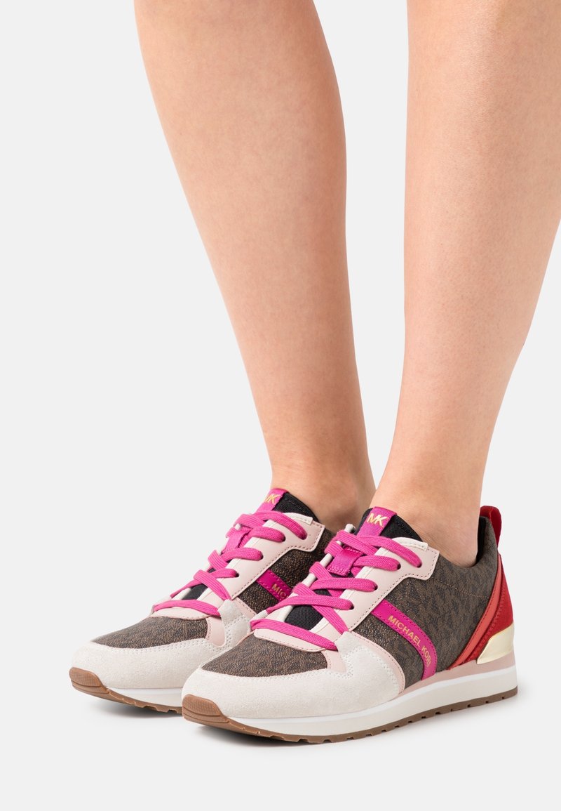 Sneaker sportive con upper in tela marrone cioccolato, lacci rosa, dettagli in suede bianco e tacco rosso. Suola in gomma per una buona aderenza.