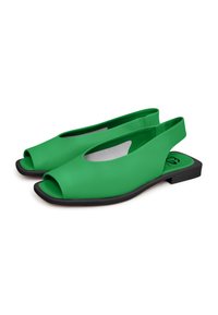 Vihreät slingback-sandaalit avoimella varpaan alueella, valmistettu sujuvasta materiaalista. Kenkässä on tasainen musta pohja ja leikattu design sivuilla.