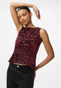 Haut sans manches bordeaux recouvert de sequins, avec un col rond et une coupe ample, associé à un pantalon noir taille haute.