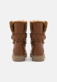 Braune Kunstleder-Ankle Boots mit weichem Fellfutter, verstellbarem Riemen und strukturierten Details auf der Rückseite. Flache Gummisohle.