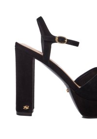 Zwarte suede hoge hak sandalen met een brede blokhak, enkelband met gouden gesp en een satijnen textuur op de bovenkant.