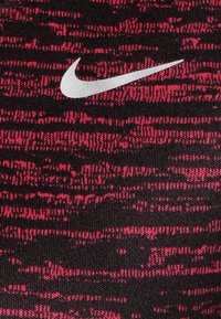 Tela con patrón rojo y negro de apariencia texturada, con un logotipo plateado de Nike exhibido de manera prominente.