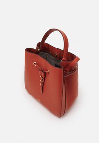 Röd läderbucketbag med texturerad finish, guldhardwaredetaljer, topphandtag och dragsko-stängning med en dekorativ tofs.