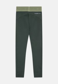 Tmavě zelené legíny Nike Pro Therma-FIT s texturovaným pasem a plochými švy, navržené pro tepelnou izolaci a sportovní nošení.