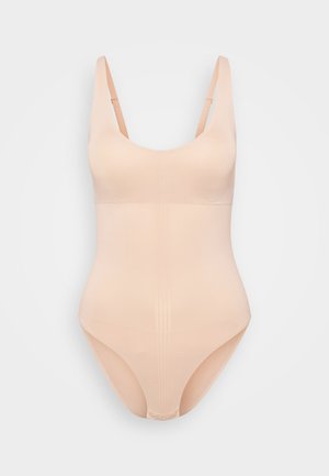 Nude bodysuit with thick adjustable straps, a scoop neck, seamless design, and smooth texture, featuring ruched detailing at the center.