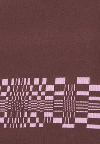 Hnědá pletenina s vzorem různých růžových geometrických tvarů a pruhů podél spodního okraje. Hladká textura.