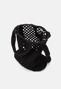 Sort hæklede tote bag med et åbent væv design, der har to robuste håndtag og en blød, tekstureret overflade.
