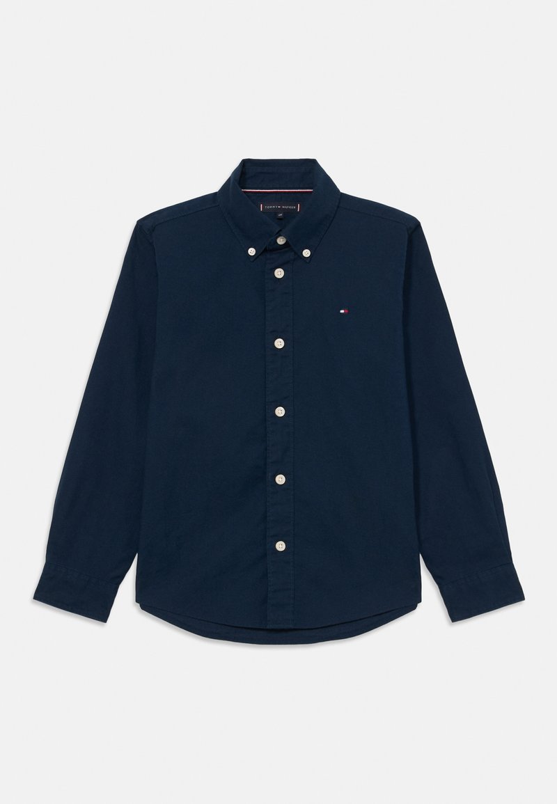 Camisa de manga longa azul-marinho em algodão. Apresenta um colarinho com botões, botões brancos e um pequeno logótipo no peito. Textura suave.