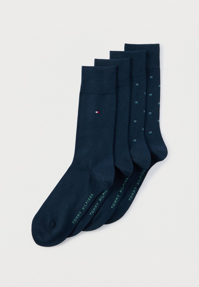 Τέσσερα ζευγάρια κάλτσες Tommy Hilfiger σε ναυτικό μπλε, δύο μονόχρωμα και δύο με μικρά μπλε και λευκά σχέδια, τοποθετημένα το ένα πάνω στο άλλο σε λευκό φόντο.