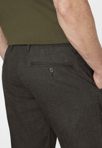 Dark gray dress pants made from a textured fabric, featuring a back pocket with a button, and a sleek, tailored design.
