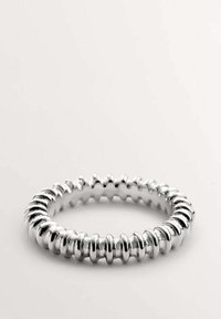 Anillo de plata con un diseño flexible y acanalado. Texturizado con alternancia de superficies lisas y ligeras hendiduras. Forma circular con un acabado brillante.