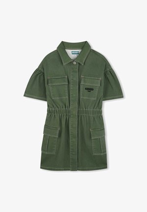 Groene dennenkatoenen jurk met kraag, elastische taille, korte pofmouwen en twee voorzakken. Kenmerkt zich door contrasterende stiksels en branding.