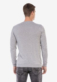Grauer langärmeliger Pullover mit Rundhalsausschnitt, gerippten Bündchen und Saum. Weiche Textur, taillierte Passform, von hinten betrachtet.