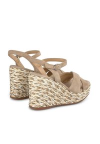 Sandalias de cuña beige con tiras y un tacón de textura trenzada y una plataforma elevada. El tacón presenta una mezcla de fibras beige y blancas.