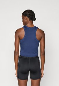 Marineblå tætsiddende tanktop med rund hals, parret med sorte kompressionsshorts med sidelommer og en glat tekstur.