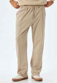 Beige, lette sweats med elastisk talje og snoretræk. Har sidesyninger som ekstra design detaljer.