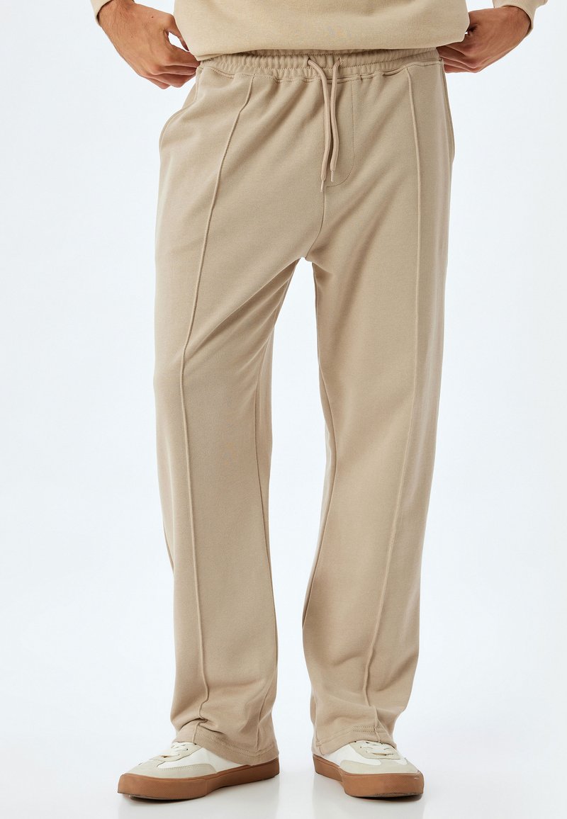 Beige, lette sweats med elastisk talje og snoretræk. Har sidesyninger som ekstra design detaljer.