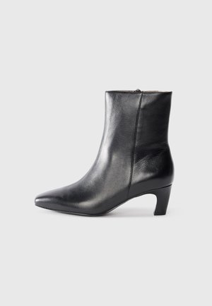 Black leather ankle boot with a pointed toe and a low heel. Smooth texture, zip closure at the back. Sleek design.