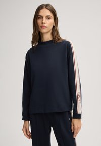 Navy sweatshirt met hoge hals, lange mouwen en witte en rode strepen langs de armen, met het "JOOP!" logo op de linker mouw.