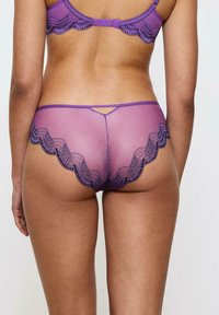 Fioletowy komplet koronkowej bielizny z falbaniastym wzorem, siateczkową teksturą i regulowanymi ramiączkami, z wycięciem na plecach.