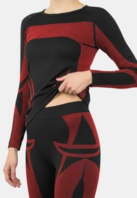 Long-sleeve activewear top in black and red, featuring a striped design. Material appears stretchy, with fitted silhouette and contrasts in color.
