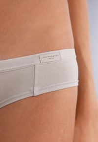 Ljusgrå underkläder gjorda av mjukt tyg, med en platt midjeband som har etiketten "intimissimi Natural" och en sömlös design.