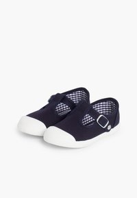 Granatowe trampki z płótna z białą gumową podeszwą, wyposażone w pasek z klamrą oraz wnętrze w kratkę. Okrągły czubek i design typu slip-on.