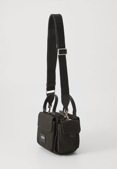 Sort stofpose med læderdetaljer, dobbelte top-håndtag og en justerbar rem. Har en lynlås lukning og en frontlomme med klap. Kompakt design.