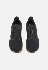 Chaussures de sport noires avec une tige en mesh, un design texturé, des lacets plats et une semelle de couleur claire. Présente un renfort au niveau du talon et un détail de logo.