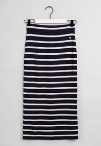 Marinblå och vit horisontellt randig knä-lång kjol hängande på en vit och svart galge mot en enfärgad bakgrund.