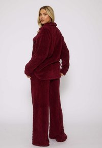 Set da soggiorno in pile bordeaux con un design a motivi a diamante testurizzati. La parte superiore presenta un colletto, mentre i pantaloni sono a gamba larga con una vestibilità comoda.
