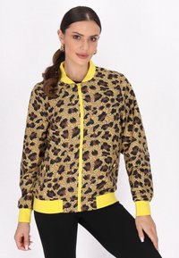 Leopardmönstrad bomberjacka i brunt och gult, med en framdragkedja, ribbade ärmslut och nederkant. Slät tyg med distinkta mönster.