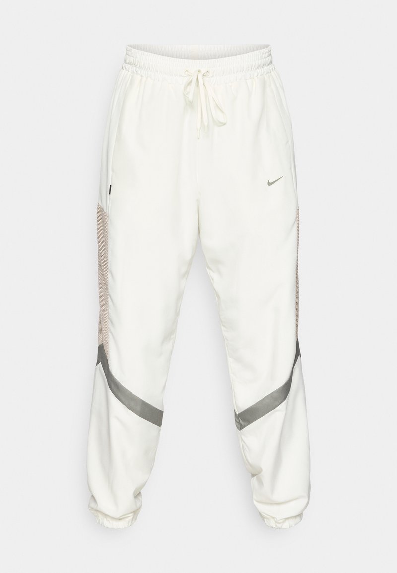 Nike-Jogginghosen in Creme mit elastischem Bund, Kordelzug, Mesh-Seiteneinsätzen und grauen Akzenten an Bündchen und Seitennaht.